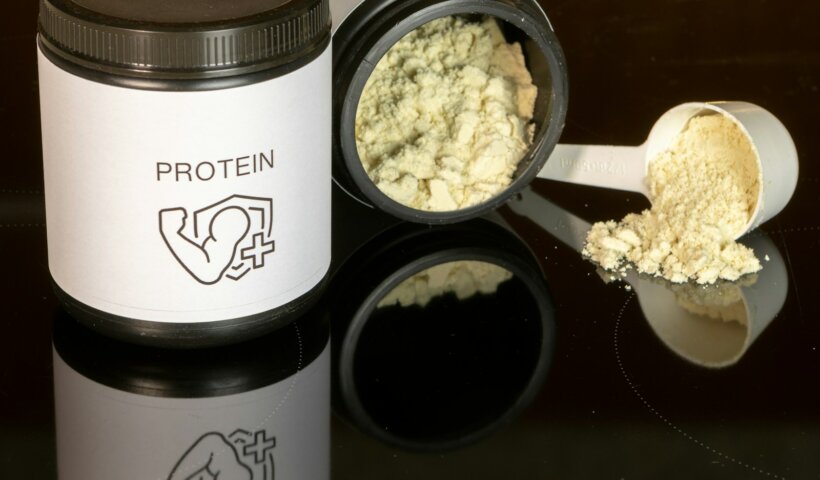 a jar of protein powder next to a spoon